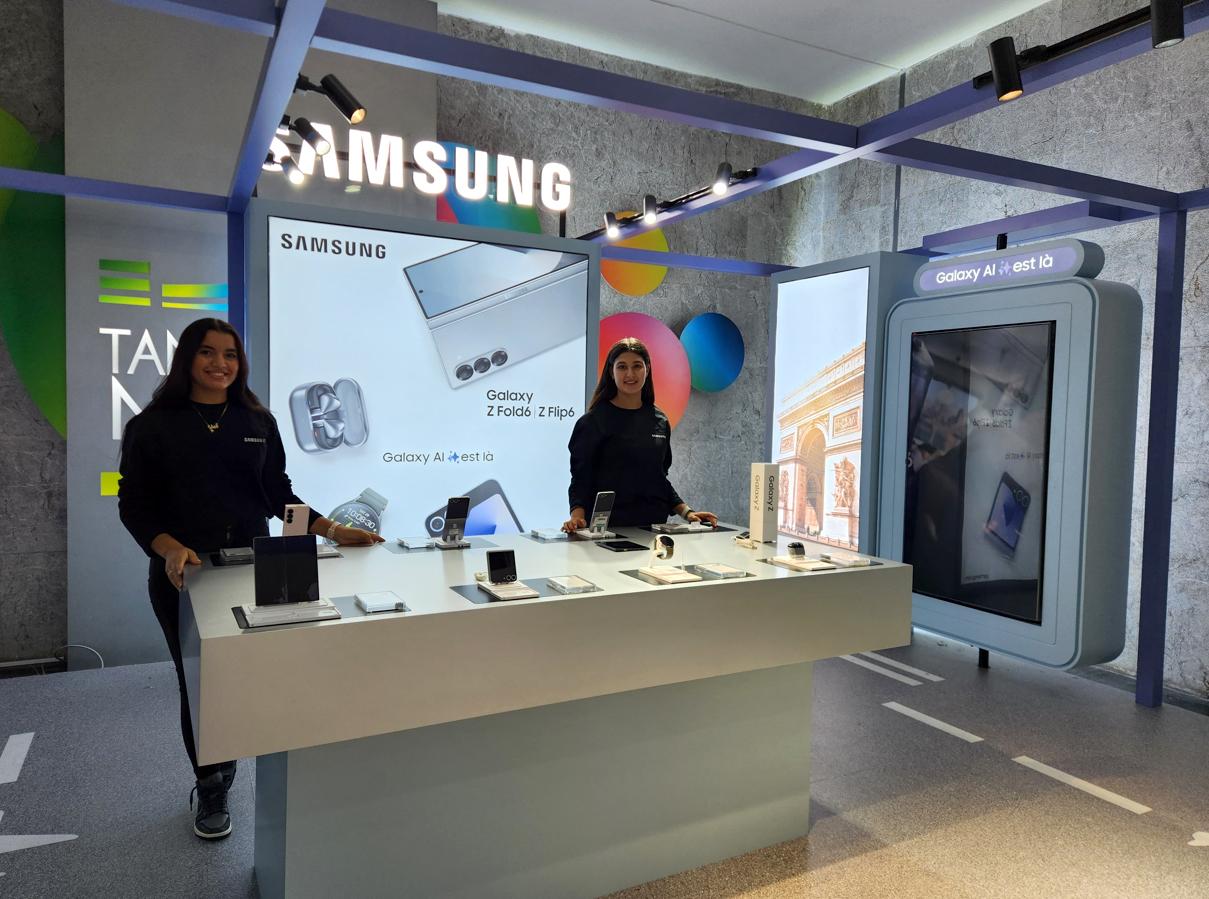 Deux hôtesses derrière la table de démonstration du corner Samsung Galaxy AI, totem écran à droite.