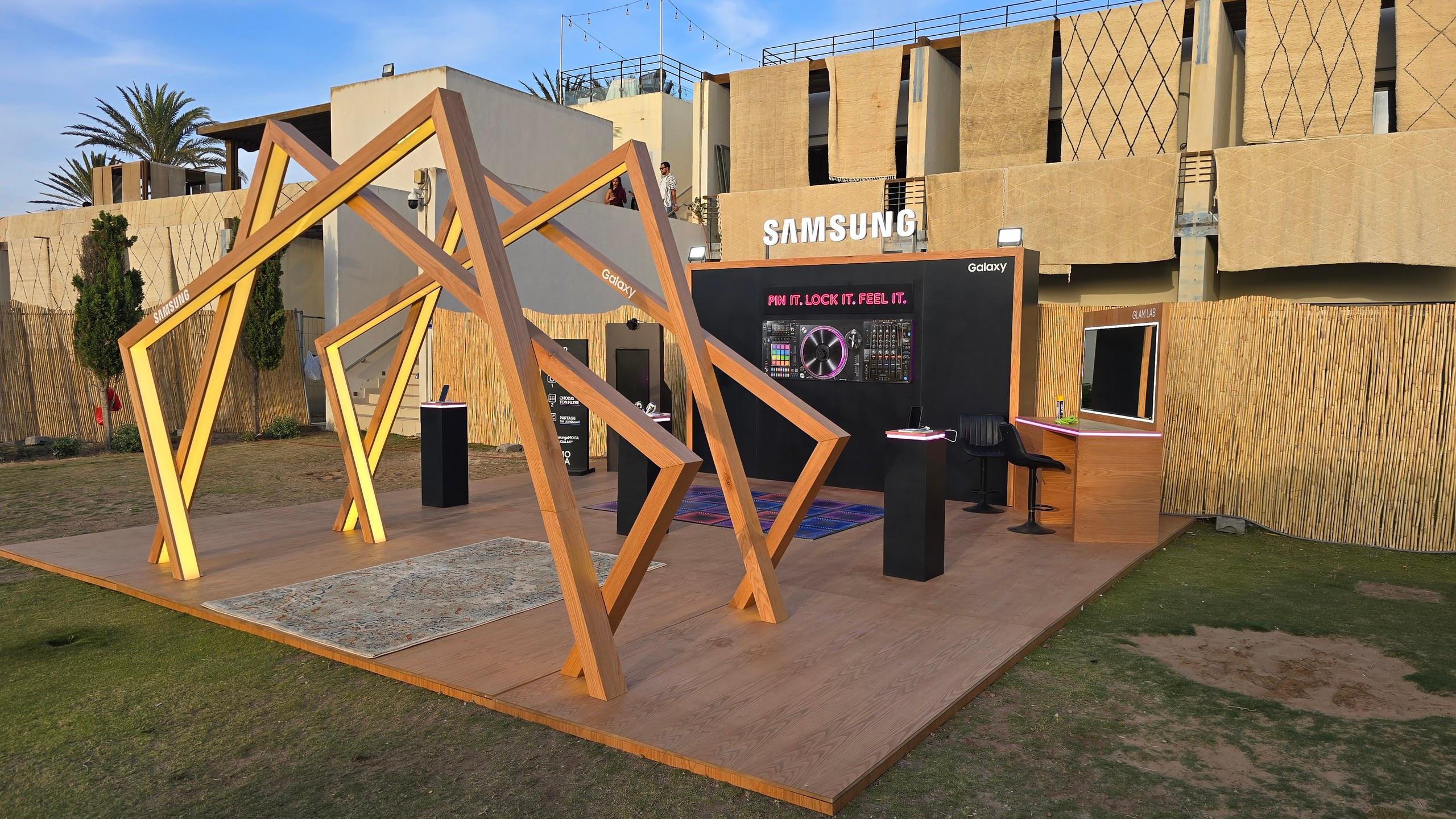 Le stand Samsung Galaxy livré, de jour : plancher bois, arches lumineuses et mur de marque.