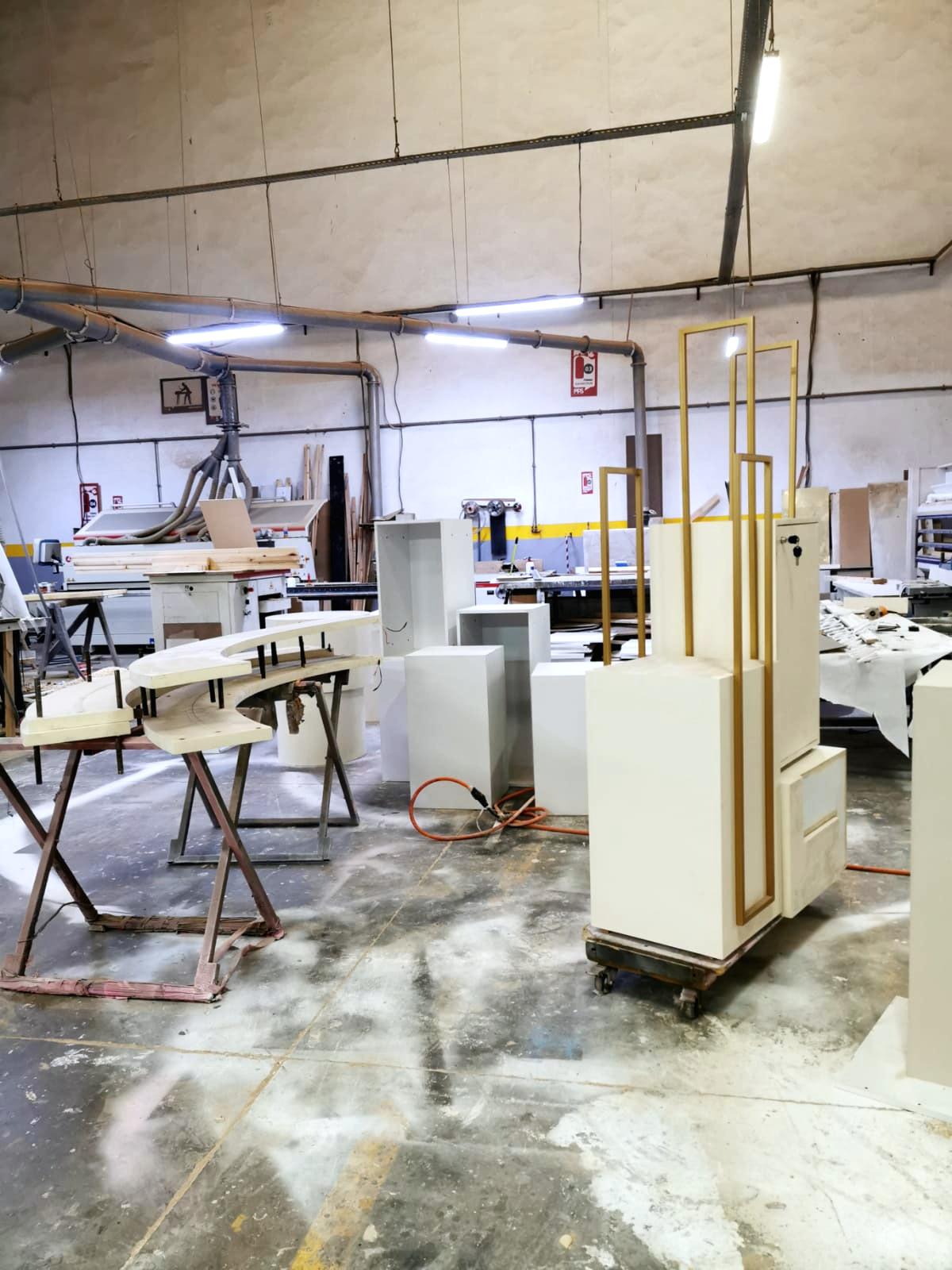 L’atelier de menuiserie : présentoirs à cadres dorés et éléments laqués en cours d’assemblage.